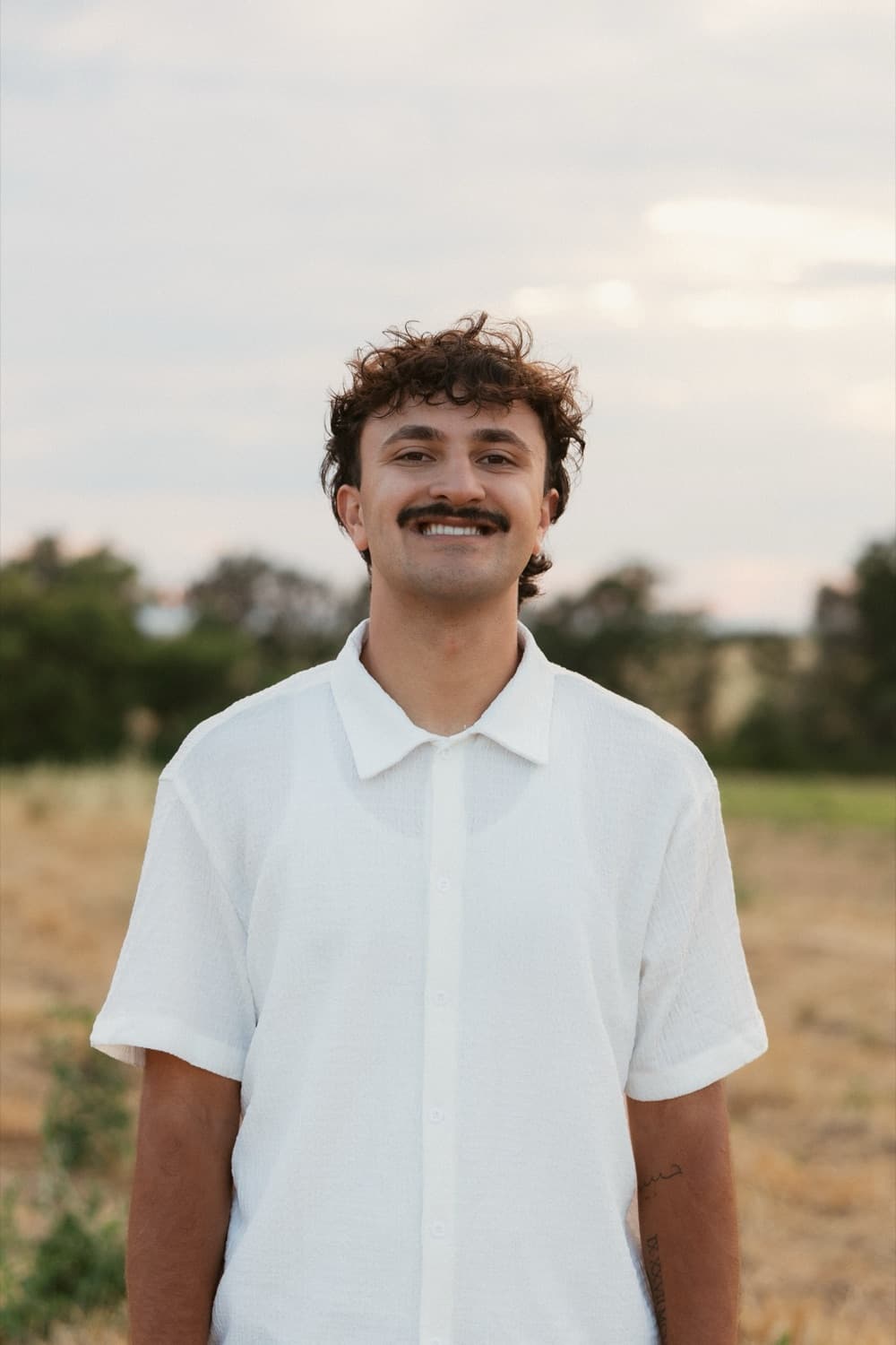 Isaac, founder of Johnson Digital Solutions, smiling in a white shirt outdoors at sunset